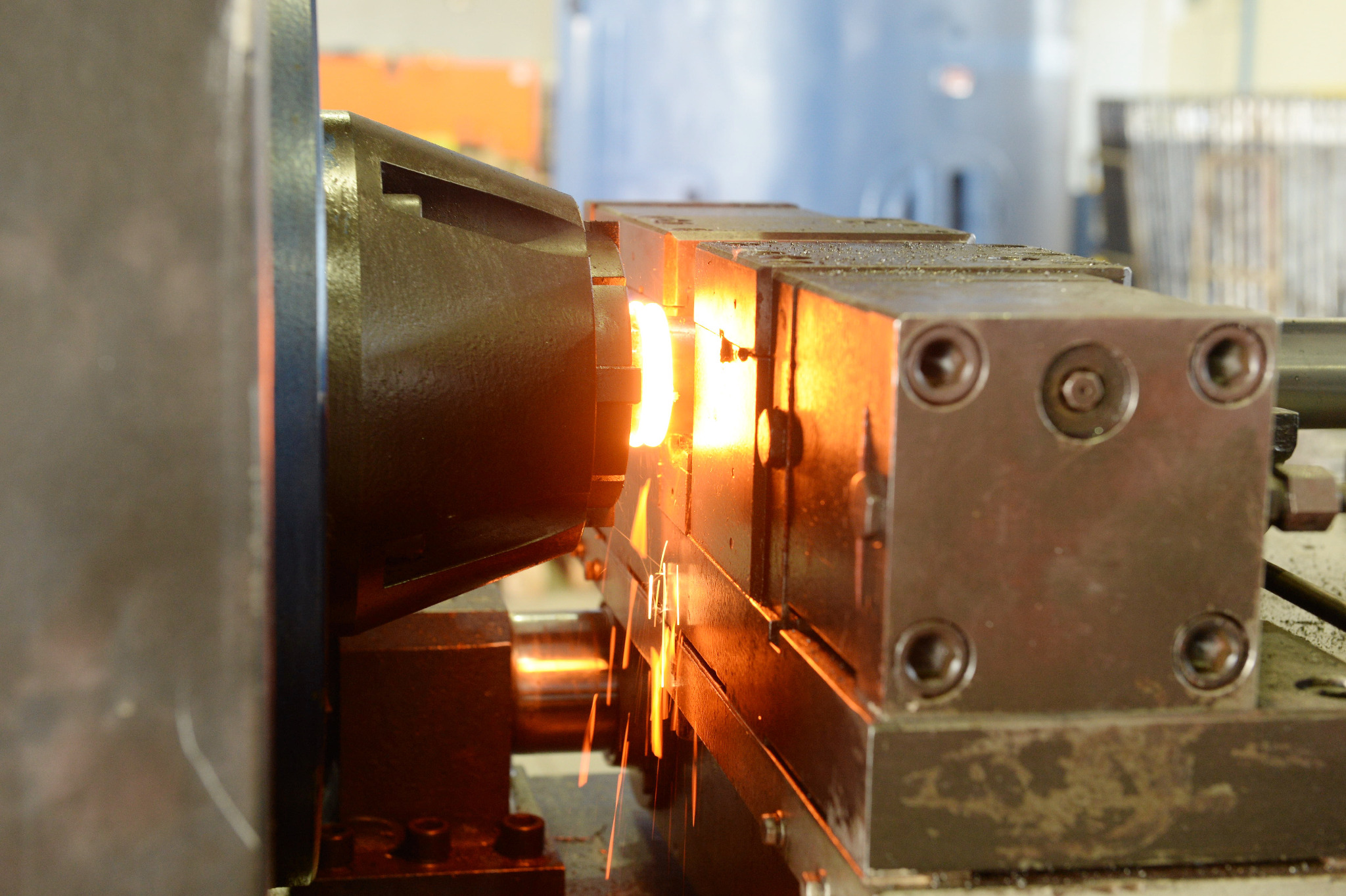 Metalowy element obrabiany w tokarce, z widocznymi iskrami podczas cięcia. Ujęcie z bliska, ukazujące detale procesu obróbki.