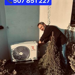 Feniks Kędra Krzysztof - Instalator przy białej jednostce zewnętrznej klimatyzacji Rotenso Ukura, montowanej na zewnątrz budynku. Numer telefonu na górze zdjęcia.