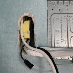 Feniks Kędra Krzysztof - Montaż klimatyzacji: przewody i uchwyt montażowy na ścianie o niebieskiej fakturze. Widoczne elementy instalacji elektrycznej i metalowy wspornik.