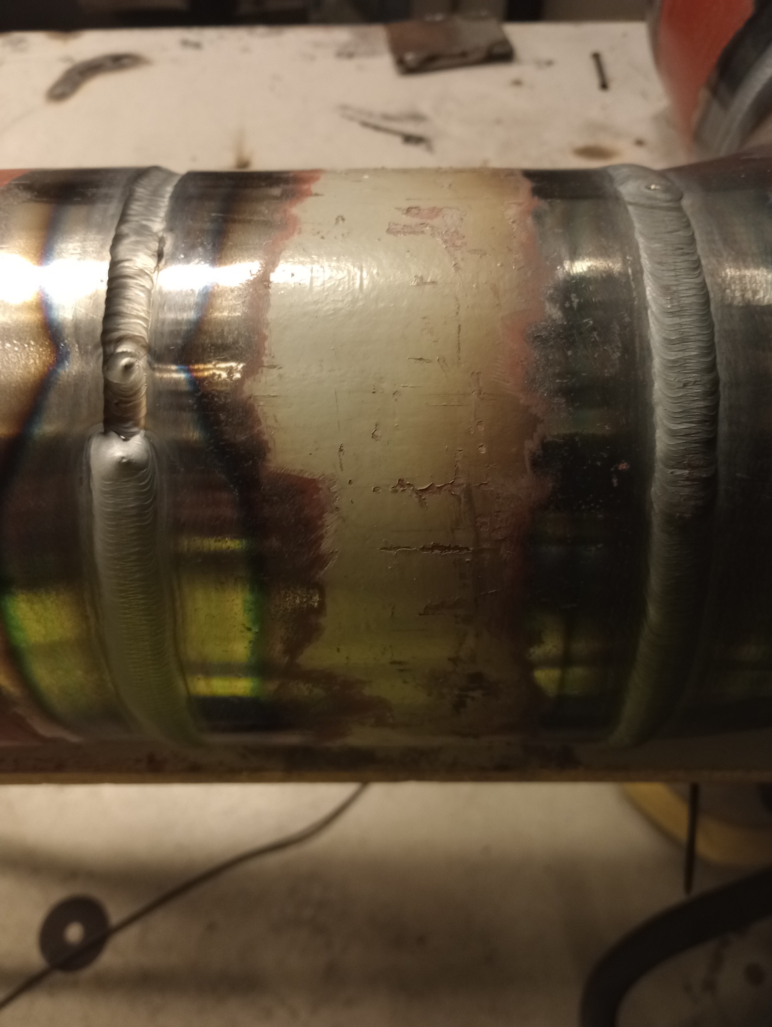 Połączenie spawane rury metalowej z widocznymi śladami ciepła i precyzyjnymi spoinami. Detal obróbki z bliska ukazuje jakość i estetykę wykonania.