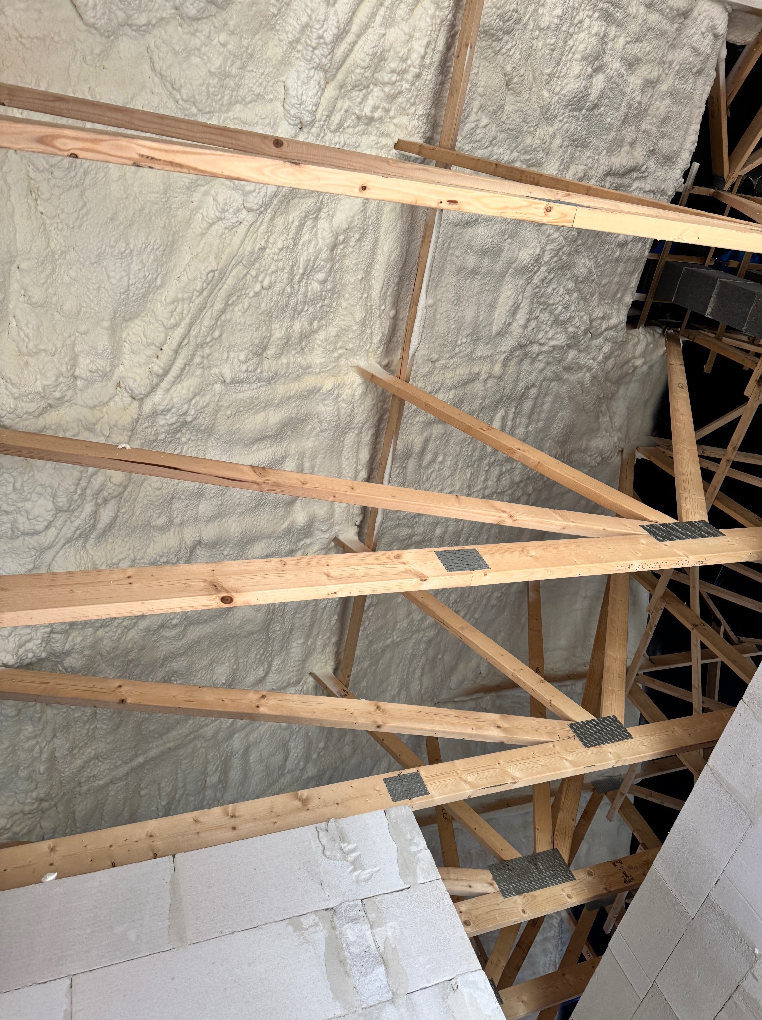 Poddasze z drewnianą konstrukcją dachu, ocieplone pianką PUR; widoczne bloczki betonowe. Wykończenie izolacji natryskowej.