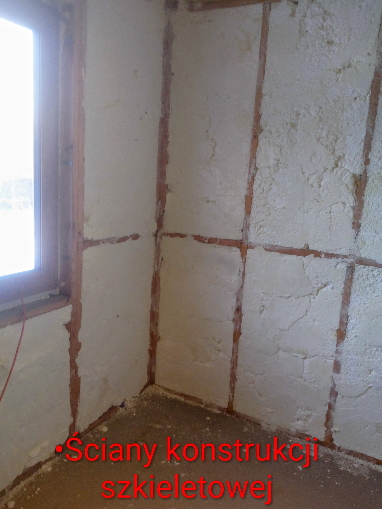 Ściana szkieletowa wypełniona pianką w Starej Kiszewie. Widoczne drewniane elementy konstrukcyjne i nałożona warstwa izolacji. Ujęcie z bliska, wnętrze budynku.