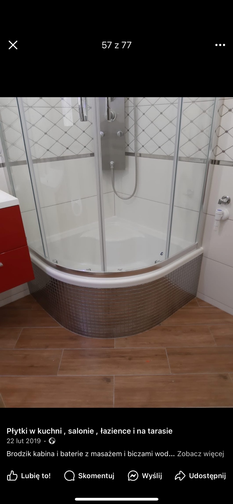 Nowoczesna kabina prysznicowa z hydromasażem, wykończona mozaiką. Widoczne brązowe płytki podłogowe i fragment czerwonej szafki umywalkowej.