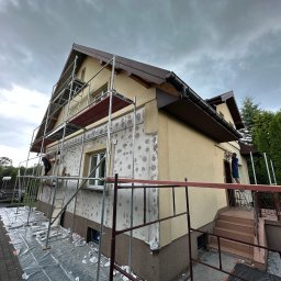 GP-BUD - Dom jednorodzinny w trakcie prac elewacyjnych: widoczne rusztowania, fragmenty ocieplenia i pracownicy. Część elewacji przygotowana do dalszych etapów prac.