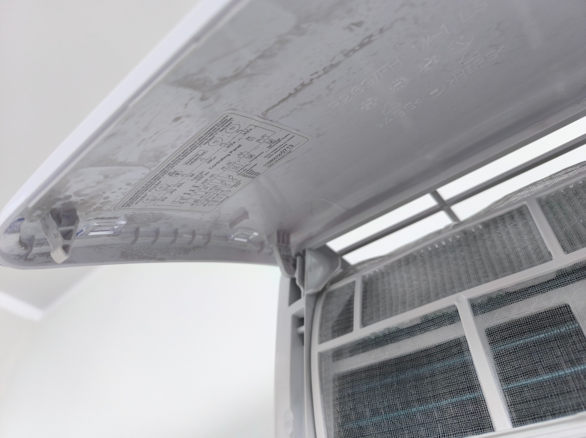 Zanieczyszczone filtry klimatyzacji, widoczne pod otwartą klapą z instrukcją. Filtr siatkowy wymaga czyszczenia, co wskazuje na potrzebę serwisu.