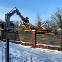 DAW-POL Sylwester Dawiec - Rozbiórka budynku w zimowej scenerii: koparka Takeuchi z hydraulicznymi nożycami tnie drewniane elementy konstrukcji. W tle resztki ścian i fragment dachu.