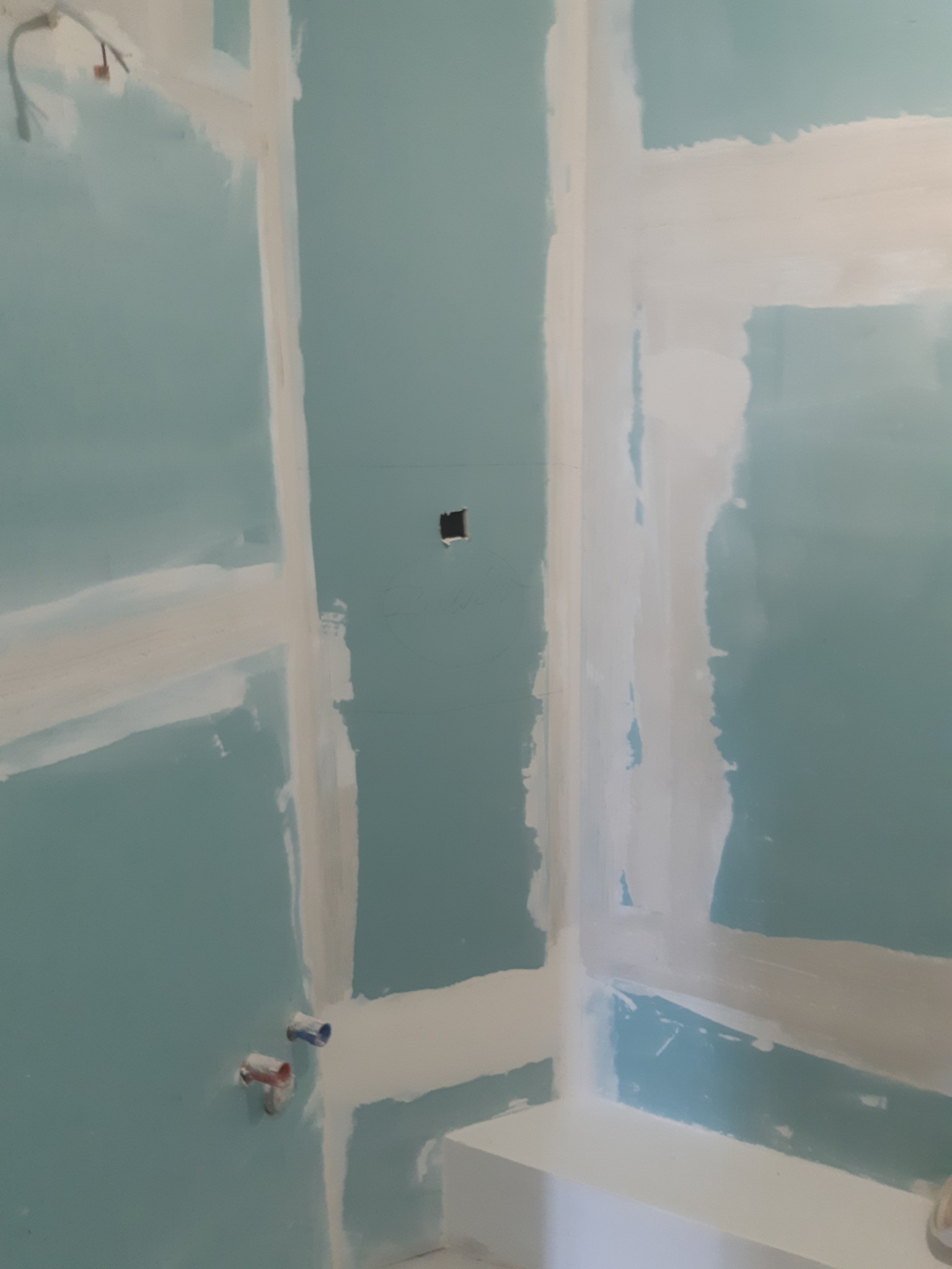 Ściany z płyt gipsowo-kartonowych po szpachlowaniu w Bolesławcu. Widoczne łączenia płyt, przygotowane do dalszych prac wykończeniowych. Instalacja wodna.