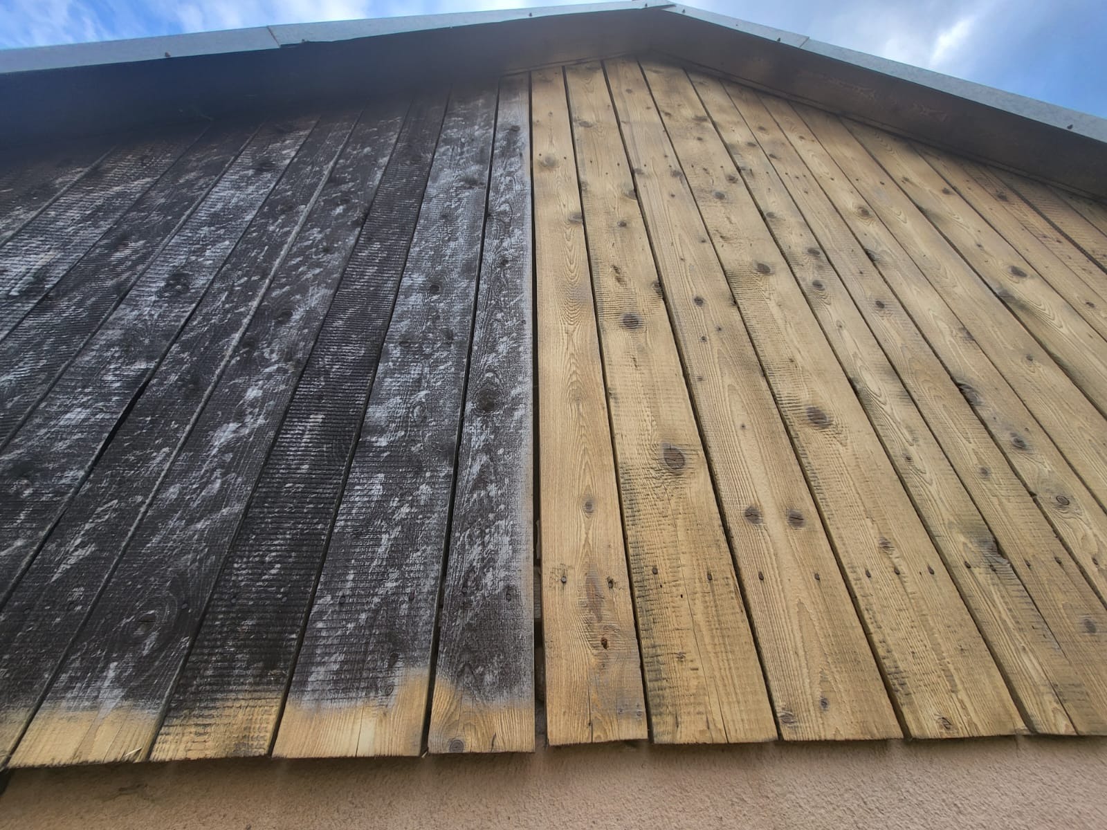 Efekt piaskowania dachu: połowa desek oczyszczona, ukazując naturalny kolor drewna, druga połowa pokryta ciemnym nalotem, widok z dołu.