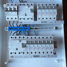 KON-TECH ADRIAN KONIECZNY - Rozdzielnica elektryczna z zamontowanymi bezpiecznikami i przewodami, widok z góry. Elementy ETI, przewody w kolorze niebieskim i czarnym.