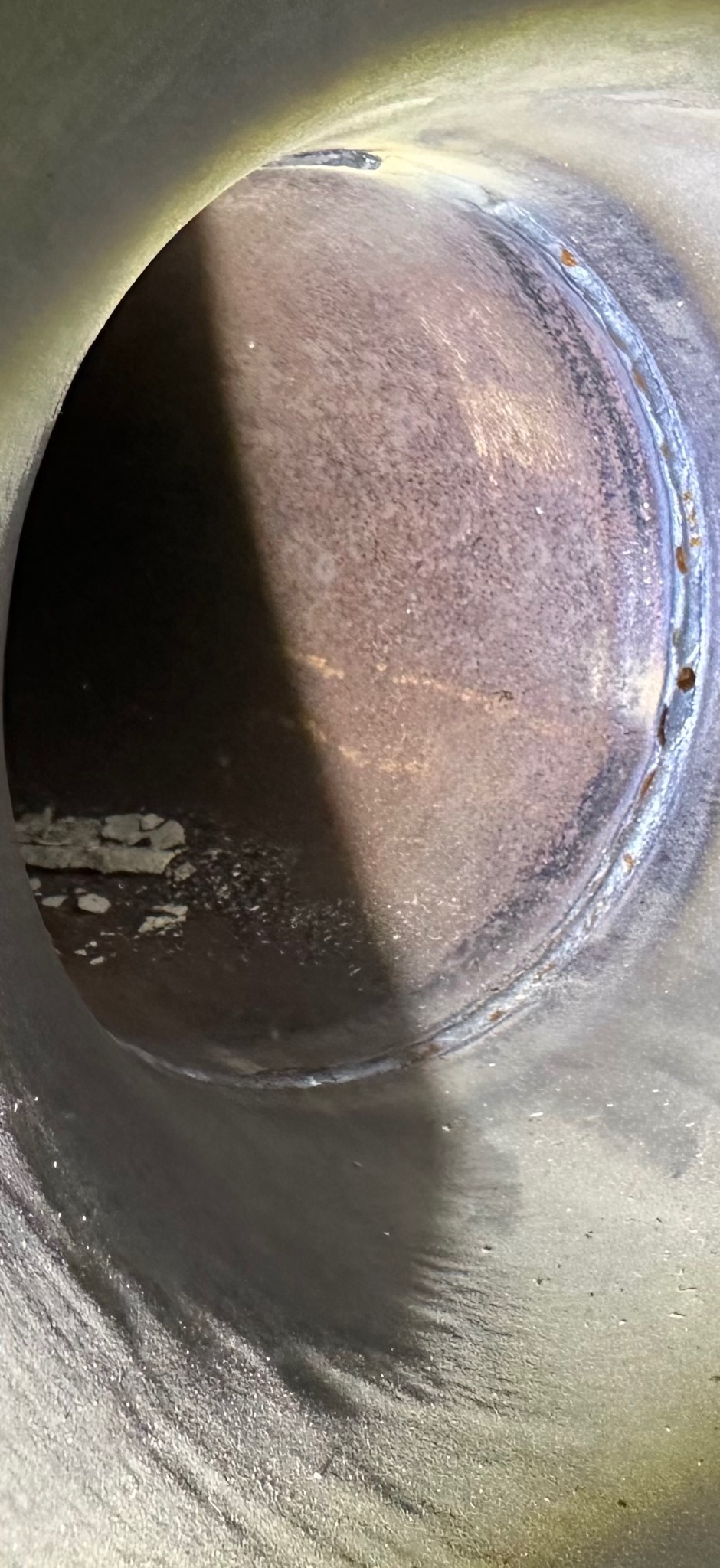 Wewnętrzny widok rury z widocznym spawem, ukazujący precyzję łączenia elementów. Metalowa powierzchnia z delikatnymi śladami obróbki i niedoskonałościami.