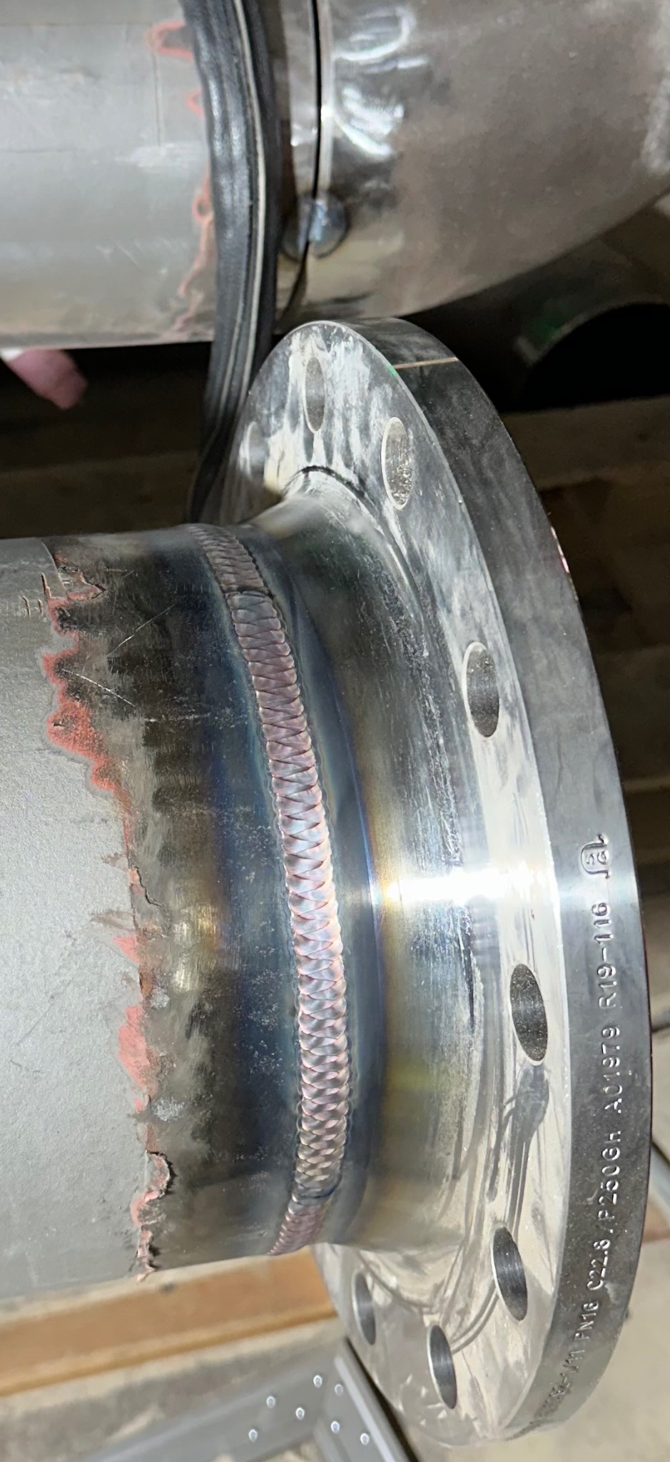 Precyzyjne spoiny na rurze z kołnierzem, widoczne detale łączenia i oznaczenia na metalu, ukazujące profesjonalizm wykonania.