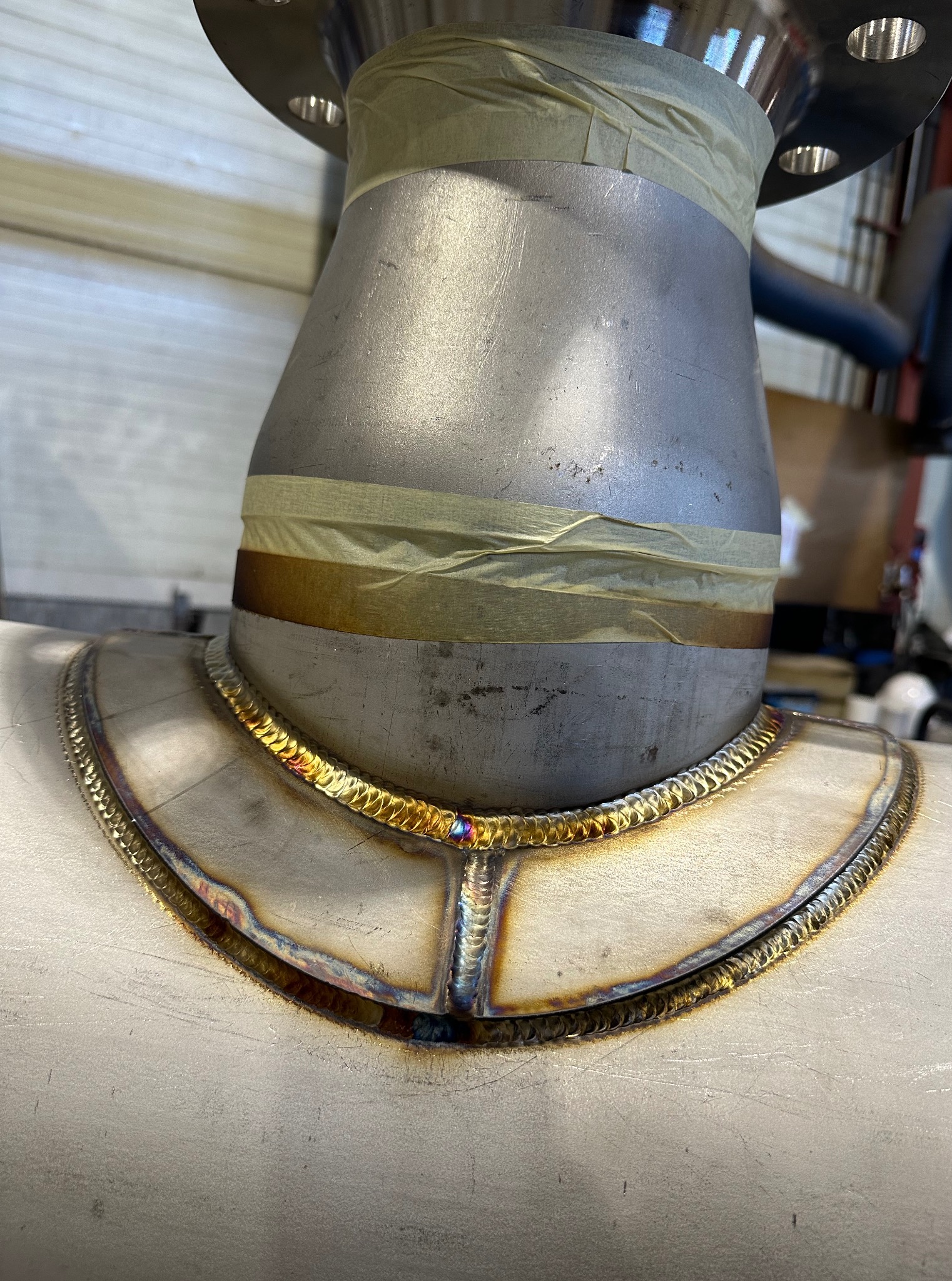 Szczegółowe zbliżenie na spawany element rurociągu ze stali nierdzewnej, z widocznymi śladami spawania i taśmą zabezpieczającą, ukazujące precyzję wykonania.