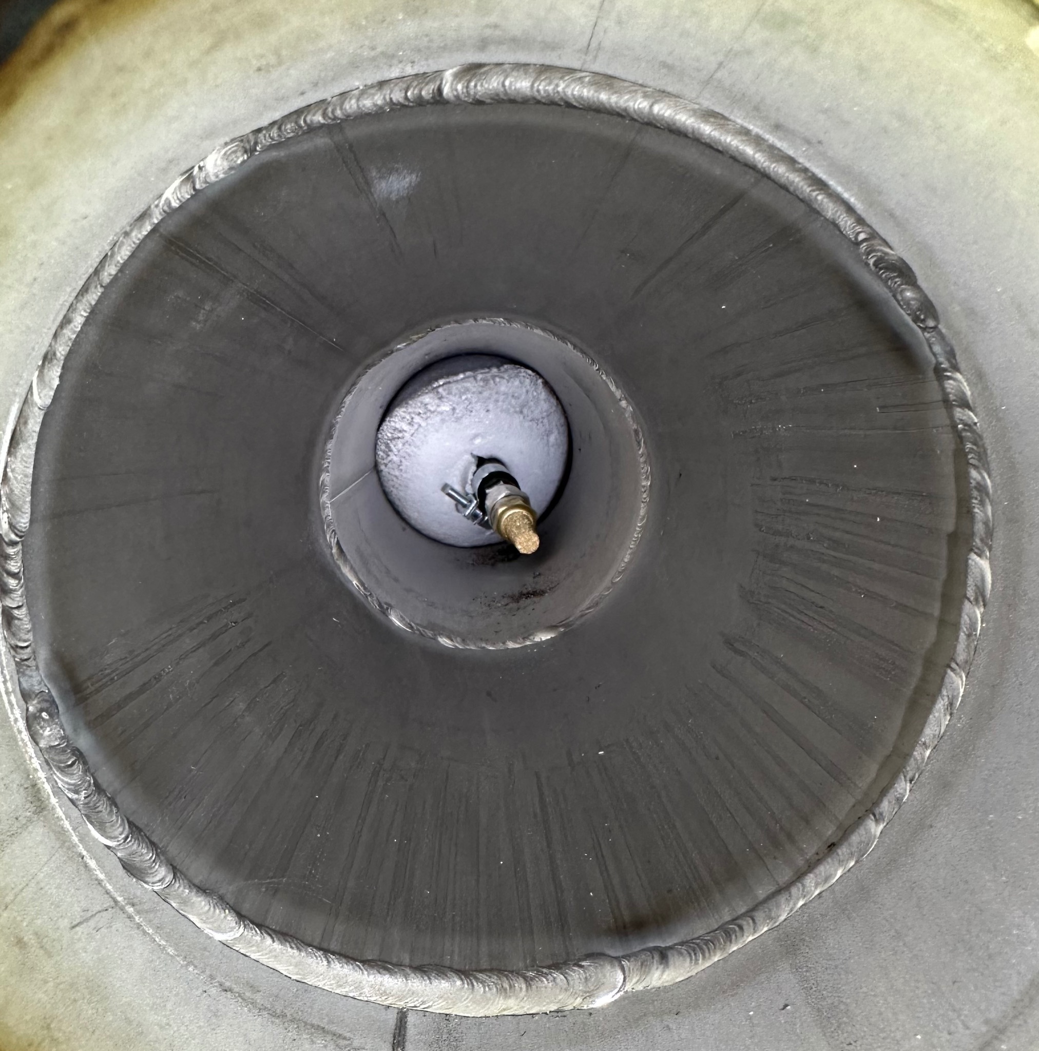 Wnętrze metalowej rury z precyzyjnym spoiwem spawalniczym na krawędziach. Widoczny element wewnątrz rury z zaworem i elementami mocującymi.