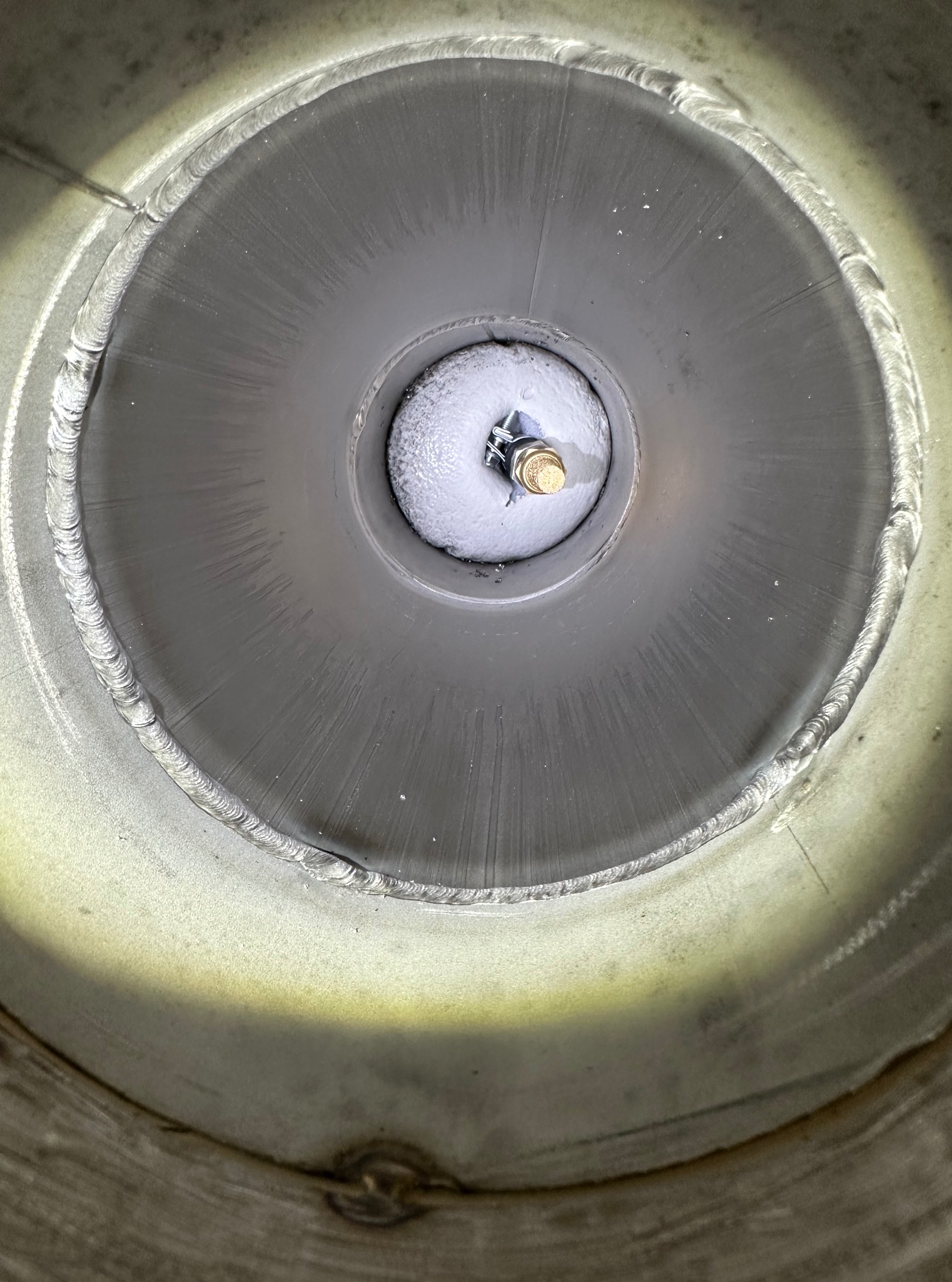 Wnętrze metalowej rury z widocznym spawem obwodowym i elementem montażowym na środku. Spaw wykonany z dbałością o detal, widoczne ślady obróbki.