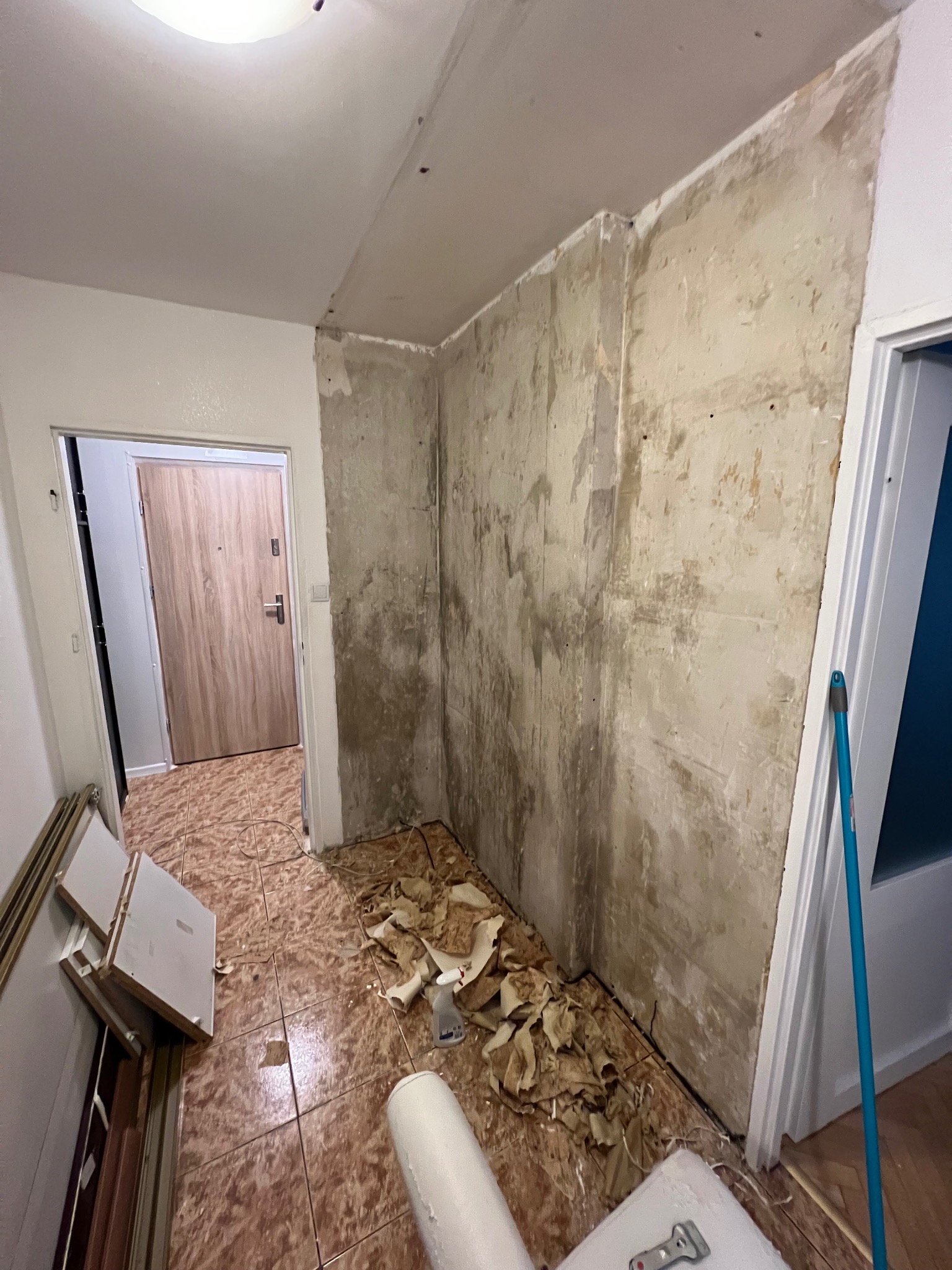 Pokój w trakcie remontu: ściany przygotowane do malowania, resztki tapet na podłodze, widoczne narzędzia i materiały budowlane. Przygotowanie do gładzi.