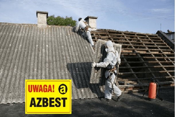 Demontaż eternitu z dachu przez dwóch pracowników w kombinezonach ochronnych. Widoczna konstrukcja dachu po usunięciu płyt azbestowych i tablica ostrzegawcza.