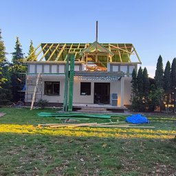 Waszka - Budowa domu jednorodzinnego w Siennie: widok na budynek w trakcie wznoszenia konstrukcji dachu, z widocznymi elementami drewnianymi i rusztowaniem.