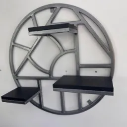 Metalowa półka ścienna w kształcie okręgu z geometrycznym wzorem i trzema czarnymi półkami, zamontowana na białej ścianie. Wykończenie w kolorze srebrnym.