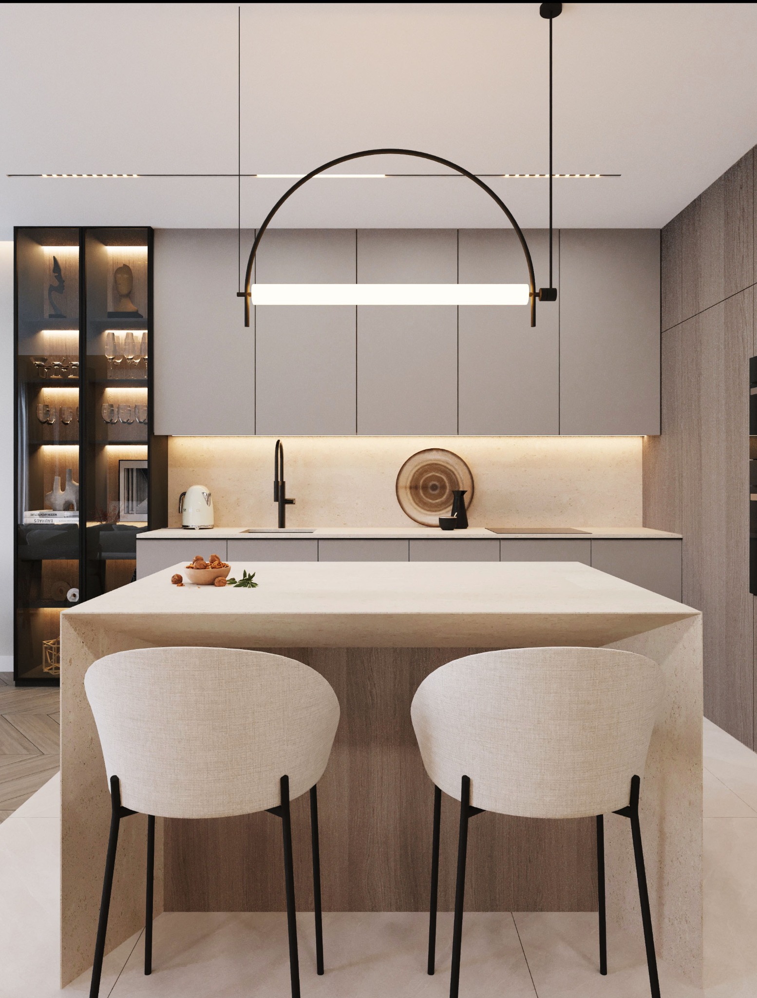 Wnętrze kuchni z wyspą i dwoma krzesłami barowymi. Nad wyspą lampa w kształcie łuku. W tle zabudowa kuchenna z przeszkloną witryną i dekoracjami.