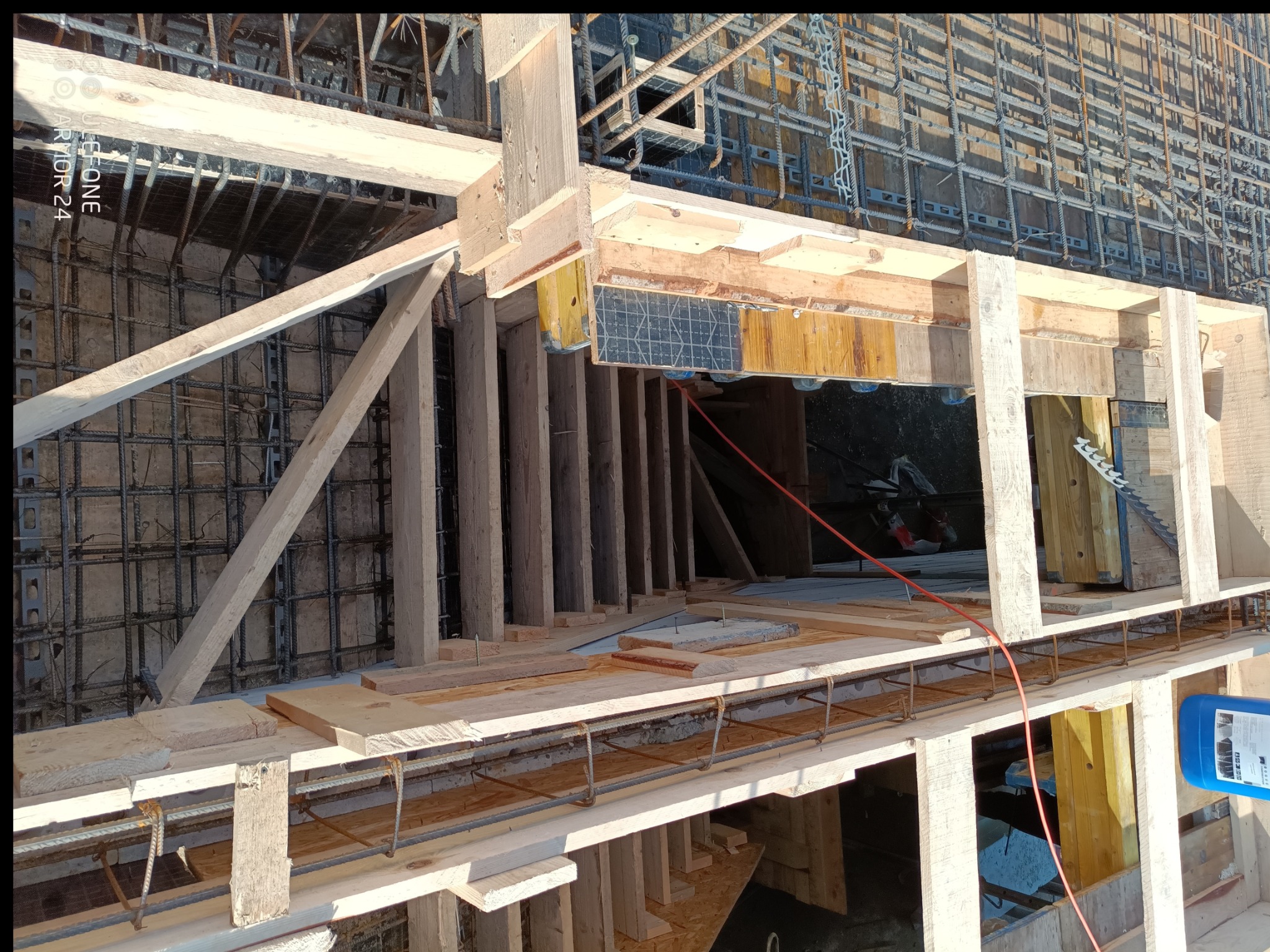 Zbrojenie i szalunek fundamentów, widok z góry. Elementy drewniane konstrukcji szalunkowej, siatka zbrojeniowa. Widoczne detale łączeń i mocowań.