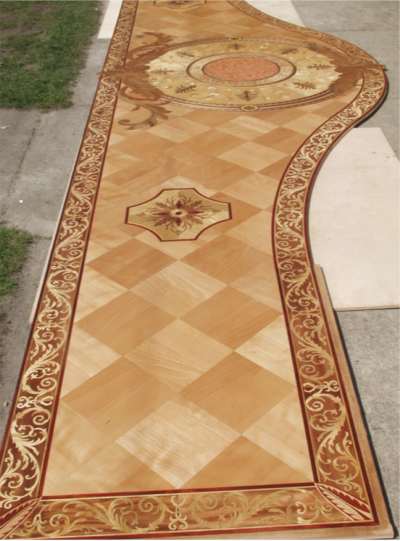 Fragment kunsztownie wykonanej posadzki z intarsjami, z wzorem szachownicy i dekoracyjnymi bordiurami oraz rozetami.