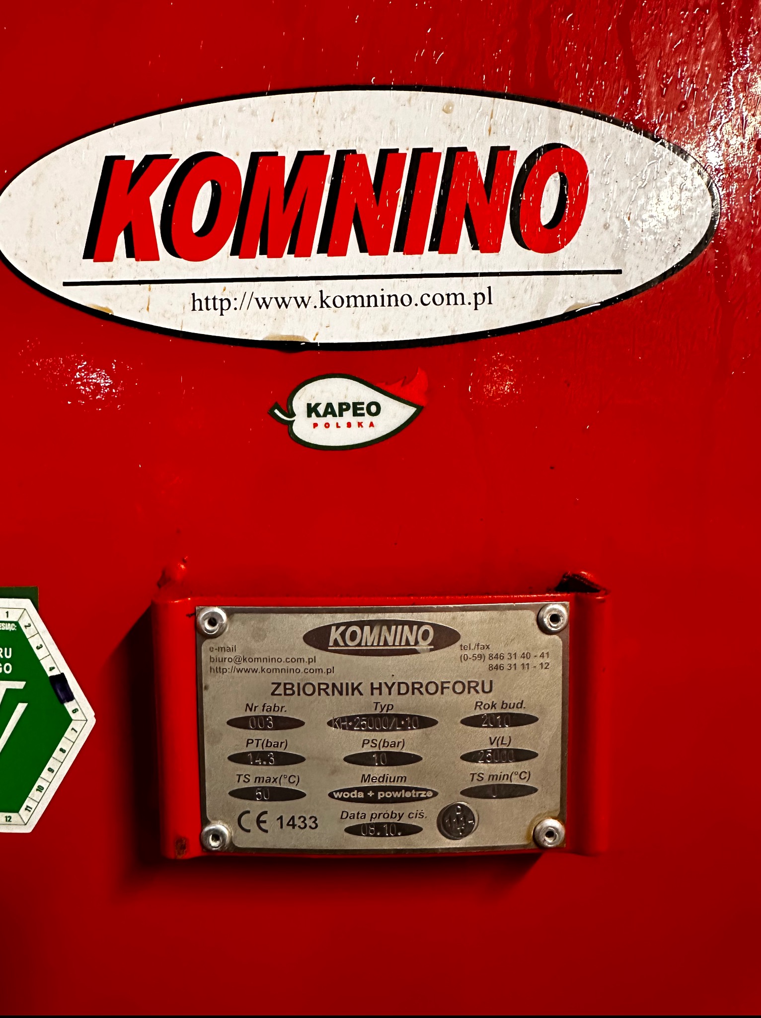 Czerwony hydrofor marki Komnino z tabliczką znamionową, na której widoczne są parametry techniczne i data produkcji: 2010. Widoczny adres strony internetowej producenta.