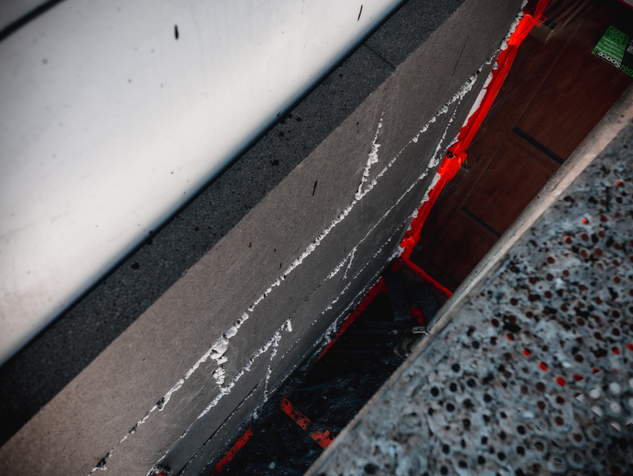 Izolacja termiczna ściany styropianem grafitowym, widoczne białe klejenie i czerwona taśma uszczelniająca, ujęcie z dołu.