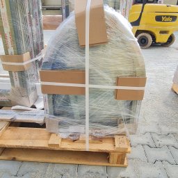 MAK Consulting p.h.u. Michał Nowak - Przygotowane do transportu okno w folii na palecie, z widocznym w tle wózkiem widłowym Yale i innymi oknami Aliplast, oczekujące na montaż.