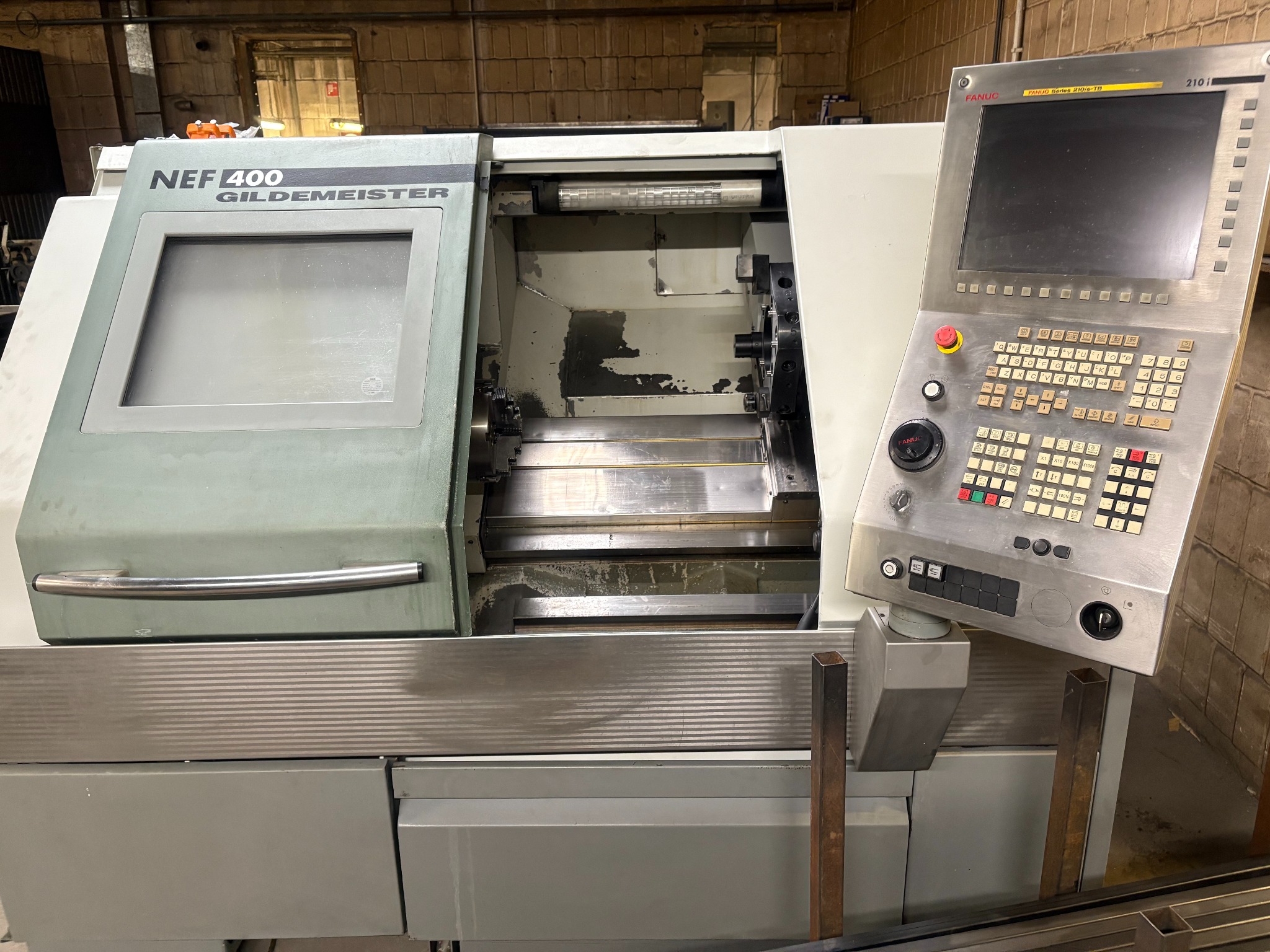 Tokarka CNC Gildemeister NEF 400 z panelem sterowania Fanuc 210i/s-TB, widoczna w warsztacie. Maszyna gotowa do pracy.