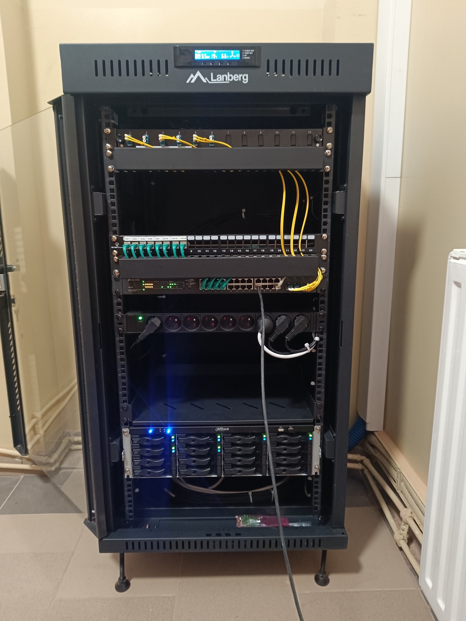 Szafa rack Lanberg z patch panelem, switchem i zasilaczem UPS w Paczkowie. Widoczne okablowanie światłowodowe i miedziane. Zasilanie awaryjne serwerowni.