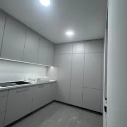 Nowoczesna, szara kuchnia z oświetleniem LED pod szafkami, marmurowym backsplashiem i błyszczącą podłogą. Minimalistyczny design z widocznymi elementami wykończeniowymi.