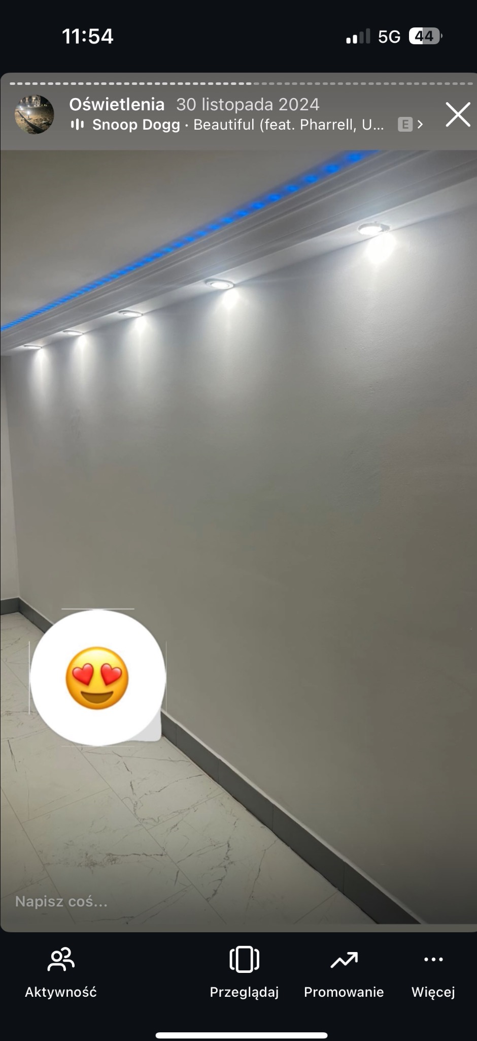 Nowoczesne oświetlenie sufitowe: rząd punktowych lamp i niebieskie LED-y w listwie. Białe ściany i marmurowa podłoga. Widok z dołu.