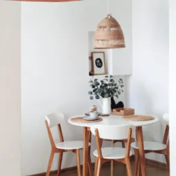 Jasna jadalnia: okrągły stół z drewnianymi krzesłami, plecione lampy i dekoracje w niszach. Minimalistyczny, skandynawski styl.