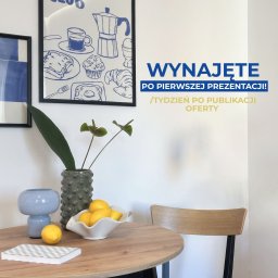 Ładniej Katarzyna Fednik - Stół z cytrynami, wazonami i plakatem 'Breakfast Club' na ścianie. Napis 'Wynajęte po pierwszej prezentacji!' sugeruje udany home staging.