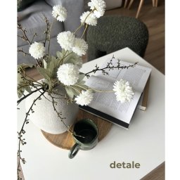 Ładniej Katarzyna Fednik - Dekoracyjny wazon z białymi kwiatami i zielony kubek na białym stoliku kawowym, otwarty album. Element wystroju wnętrza w neutralnej kolorystyce.