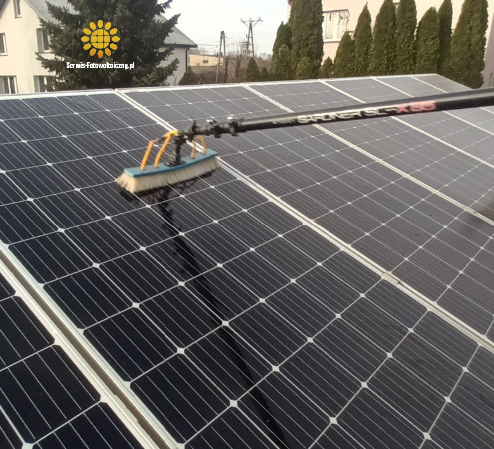 Czyszczenie paneli fotowoltaicznych szczotką na wysięgniku, widoczne panele na dachu budynku. Dedykowana szczotka do mycia paneli fotowoltaicznych.