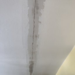 BartexDesign - Szpachlowana szczelina na suficie, widoczne ślady po pęknięciu. Jasne wnętrze, sufit w trakcie naprawy, przygotowany do dalszych prac wykończeniowych.