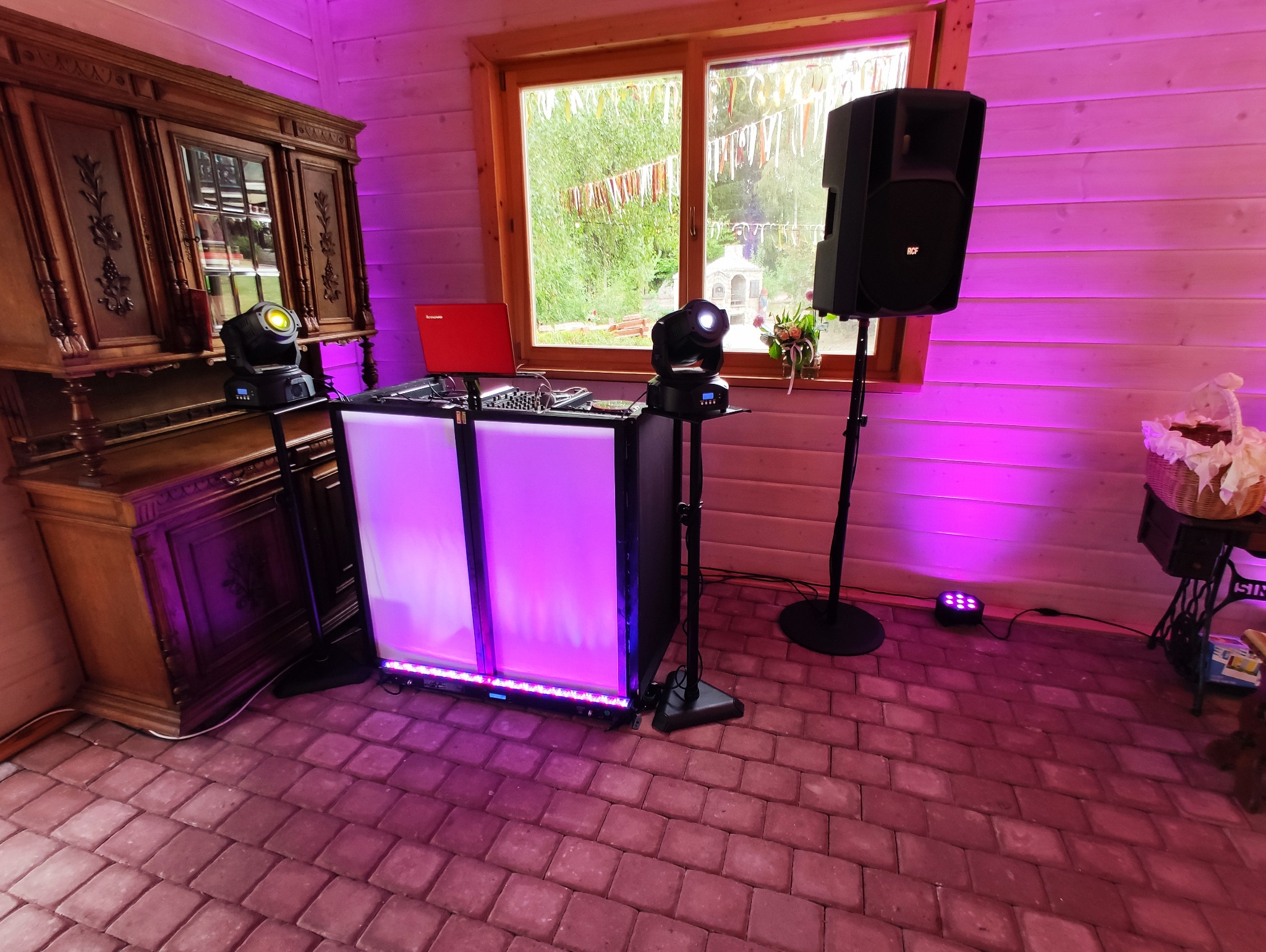 Profesjonalne nagłośnienie i oświetlenie eventowe w rustykalnym wnętrzu z oknem, w tle dekoracyjne wstążki, tworzące kameralną atmosferę.