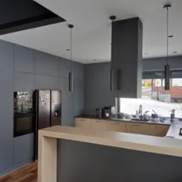 Nowoczesna kuchnia z szarymi frontami i drewnianym blatem, wyspą. Widoczne oświetlenie punktowe i przeszklona witryna z barkiem. Za oknem zimowy krajobraz.