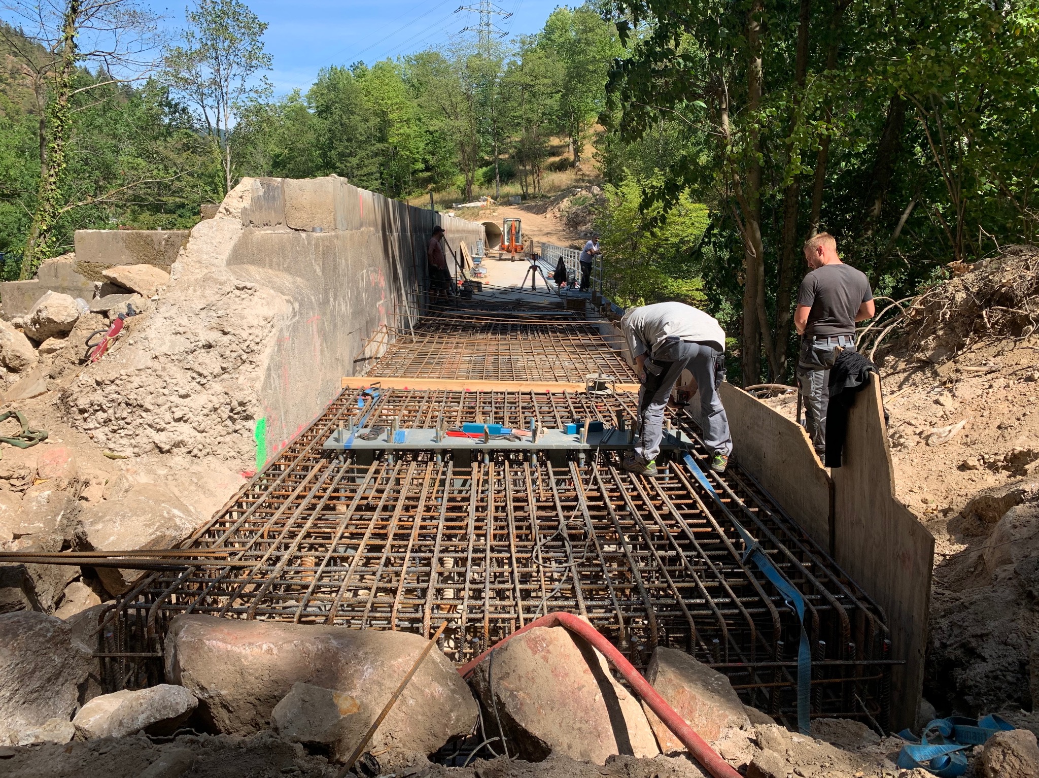 Zbrojenie konstrukcji w Gołkowicach Dolnych. Widoczna stalowa siatka zbrojeniowa, pracownicy budowlani oraz ciężki sprzęt w tle. Prace ziemne w toku.