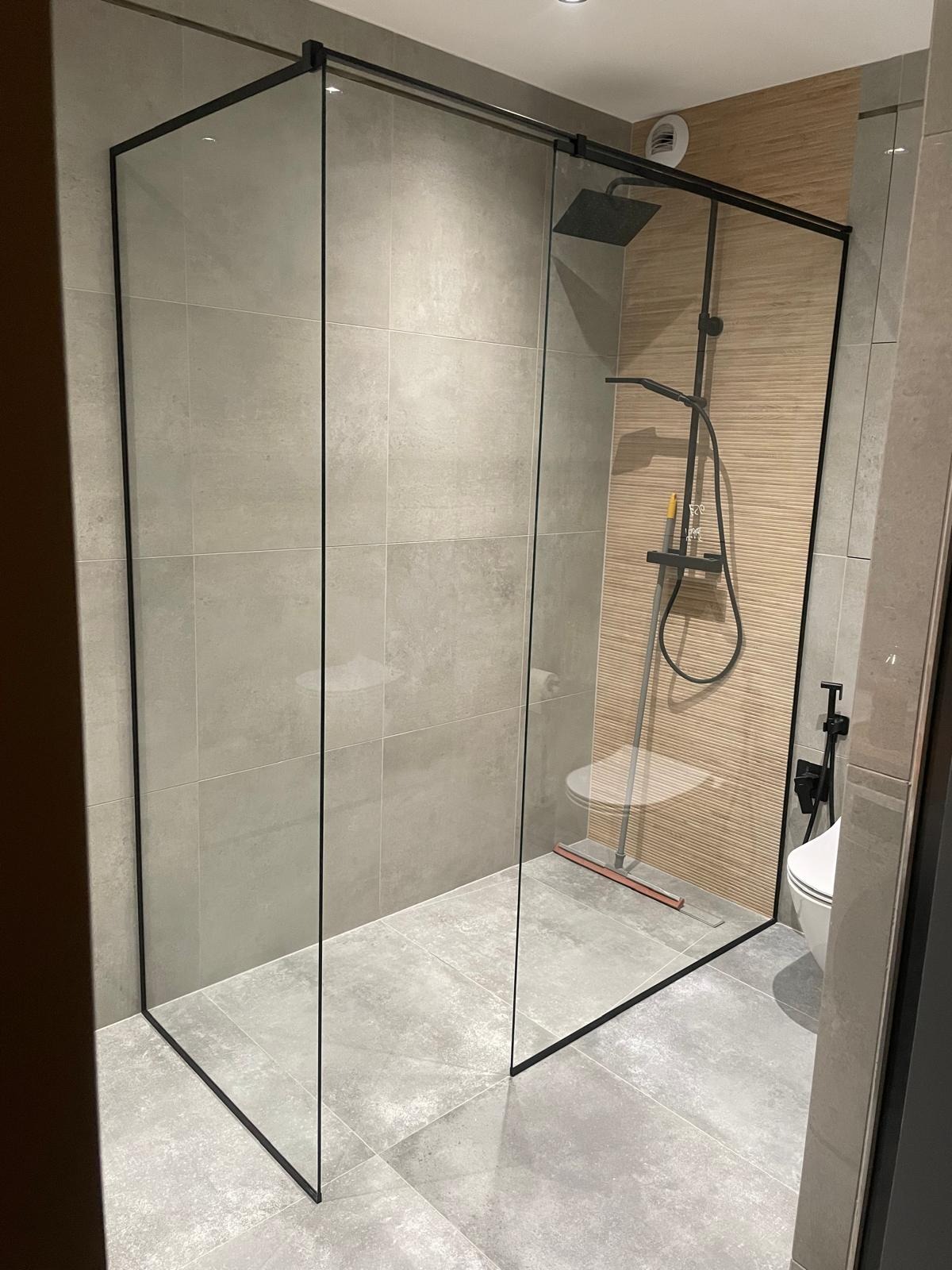 Kabina prysznicowa ze szkła hartowanego, czarne ramy, szara płytka, deszczownica. Nowoczesna łazienka po remoncie.