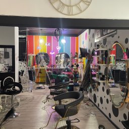 Serhii Burlin - Wnętrze salonu fryzjerskiego z kolorowymi ścianami, lustrami i fotelami. Widoczne narzędzia fryzjerskie i dekoracje, tworzące unikalny, artystyczny wystrój.