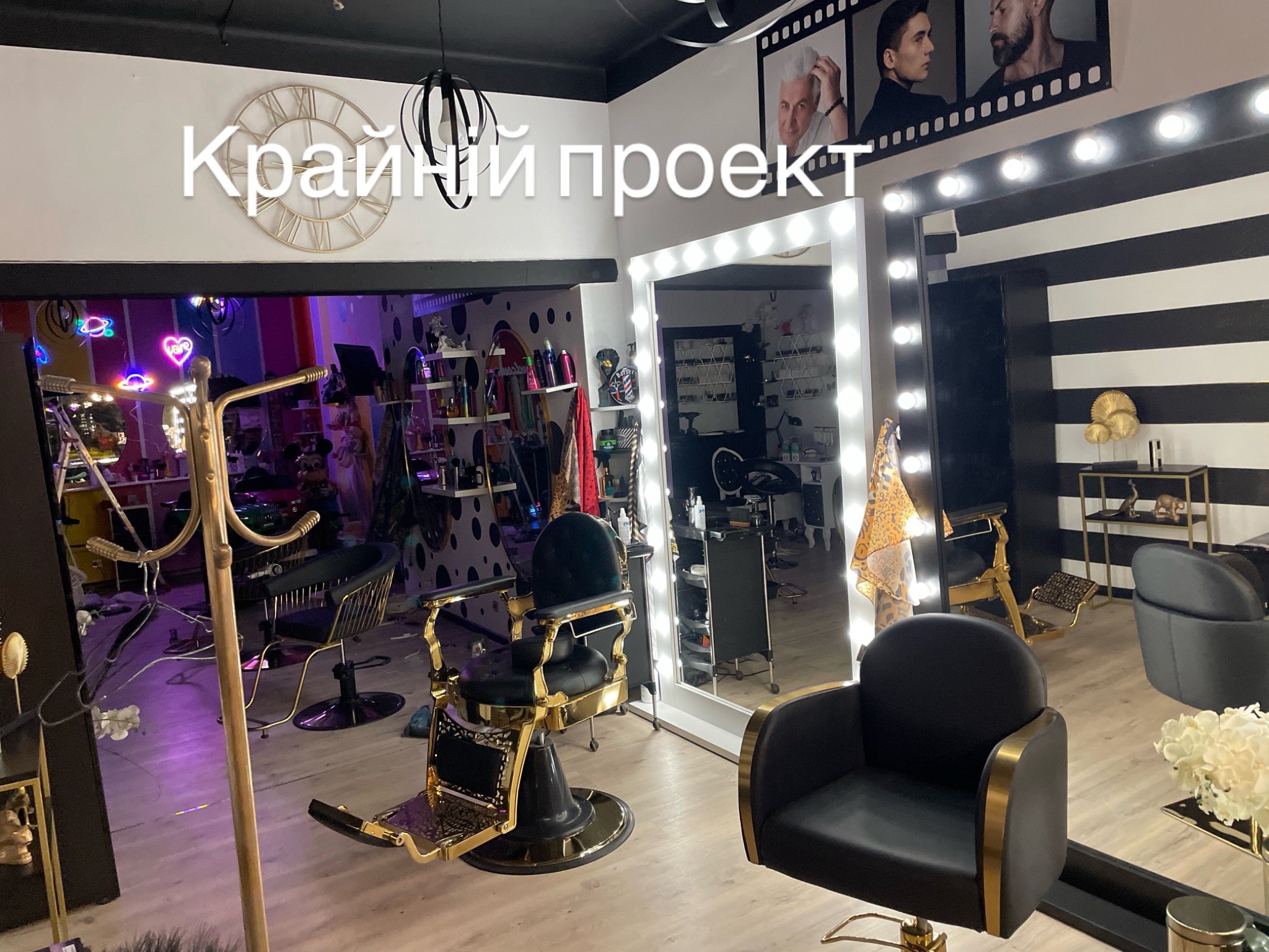 Nowoczesne wnętrze salonu fryzjerskiego z czarno-złotymi fotelami, lustrami z oświetleniem i dekoracyjnymi elementami, jak zegar i neonowe ozdoby.