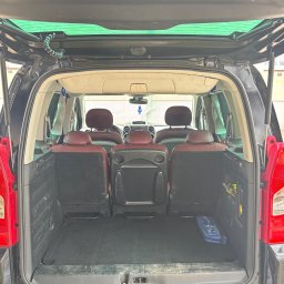 ComfortDrive Sanckler - Otwarty bagażnik czarnego minivana z widocznymi trzema rzędami siedzeń, apteczką i hakiem holowniczym. Widok z tyłu pojazdu.