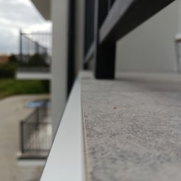 Nowa posadzka z kafli na balkonie, wykończona listwą okapową.