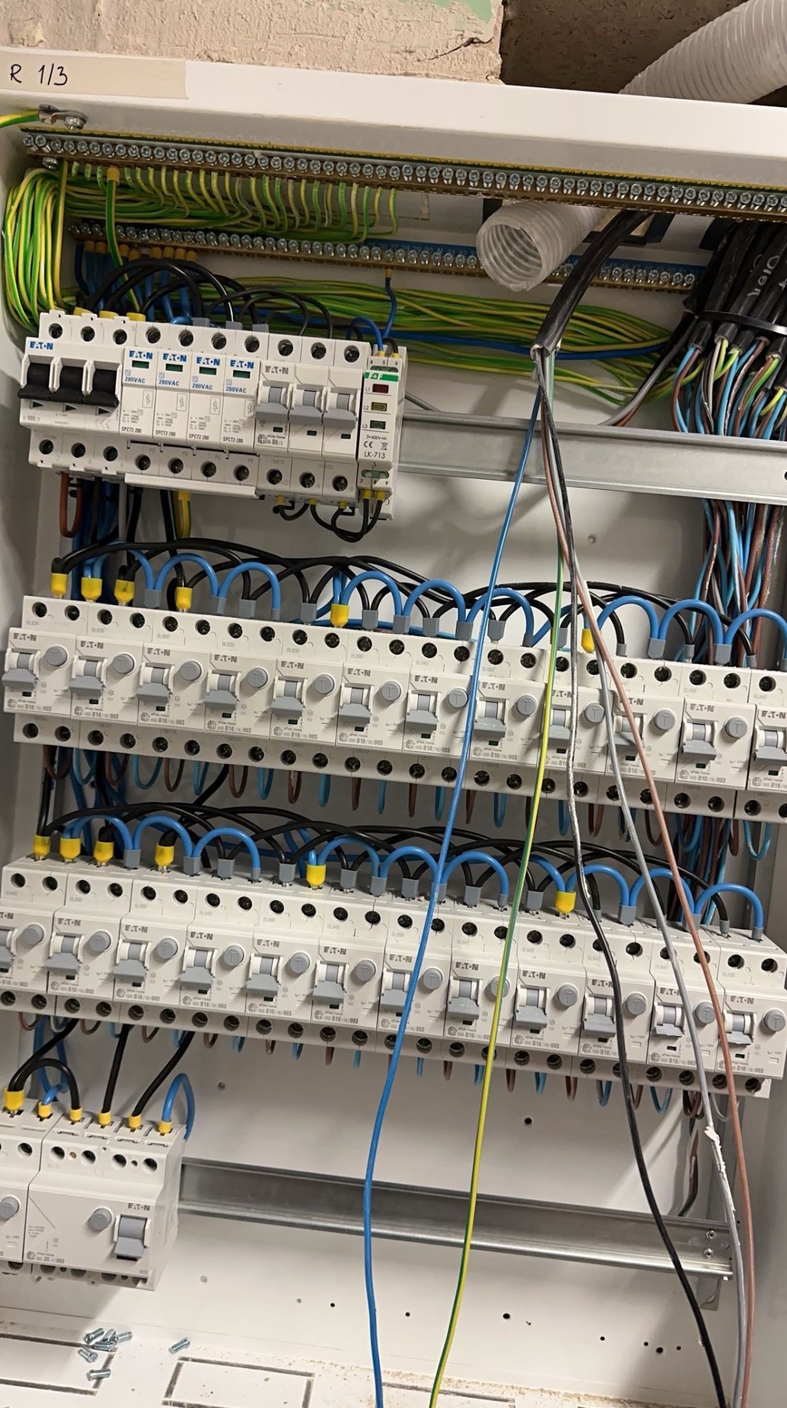 Rozdzielnia elektryczna Eaton z licznymi bezpiecznikami i przewodami w różnych kolorach, widok z bliska na instalację w trakcie prac.