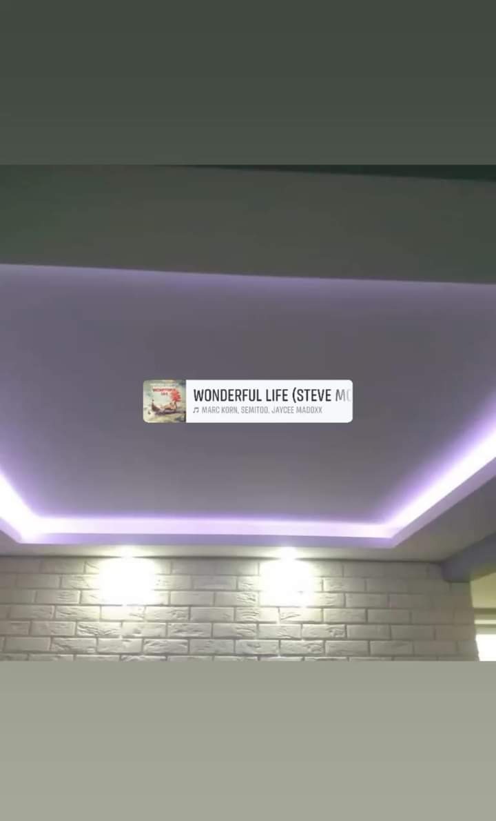 Podwieszany sufit z oświetleniem LED w kolorze fioletowym, ściana wykończona białą cegłą dekoracyjną. Nowoczesne wykończenie wnętrza po remoncie.