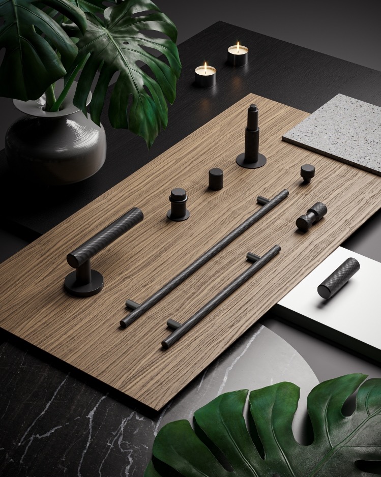 Czarne, teksturowane okucia do drzwi na drewnianej desce w Długołęce. Prezentacja klamek, gałek i zamków w minimalistycznej aranżacji z roślinami i świecami.