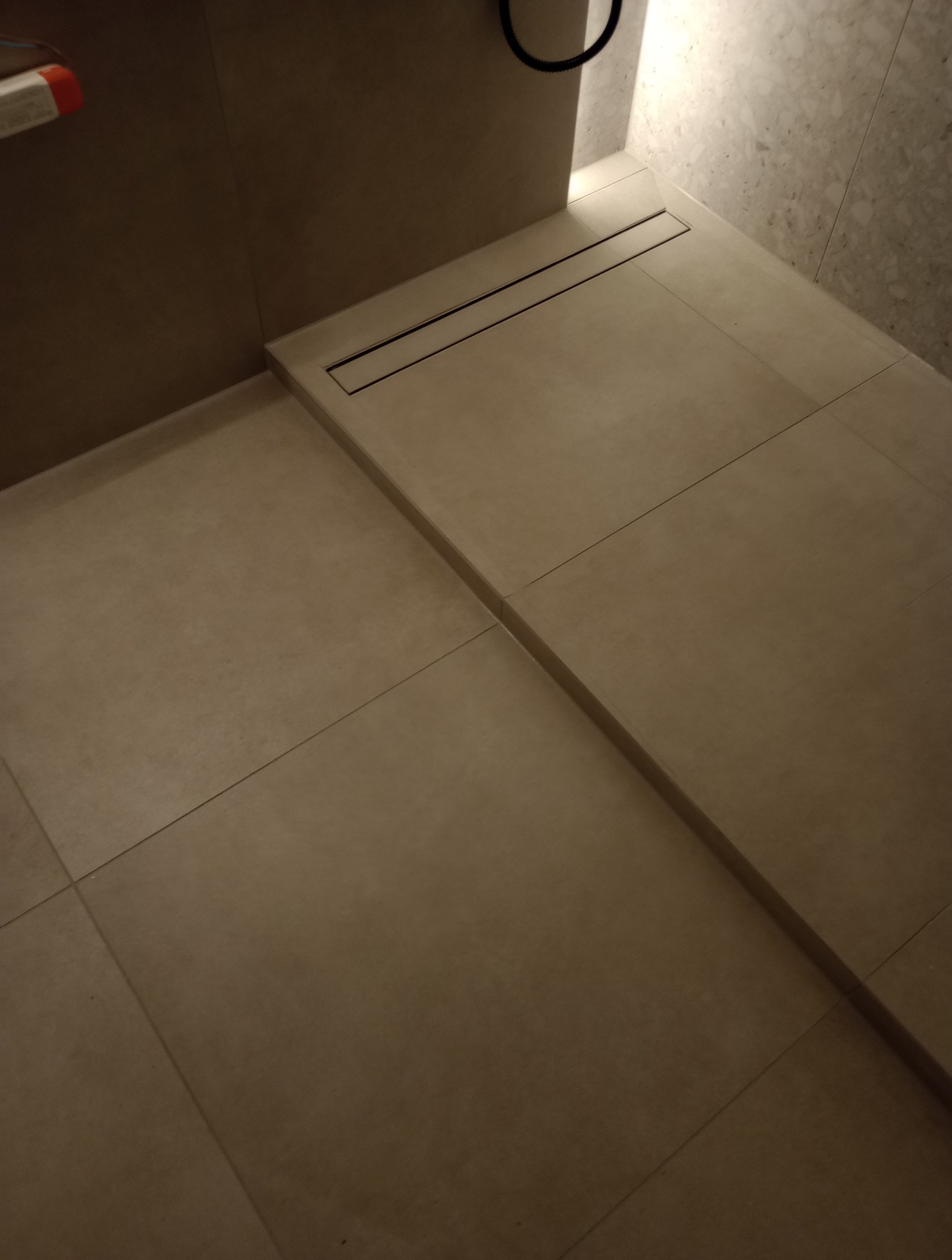 Wykończona strefa prysznicowa z odpływem liniowym w Choszcznie. Beżowe płytki podłogowe i ścienne tworzą minimalistyczny design łazienki.