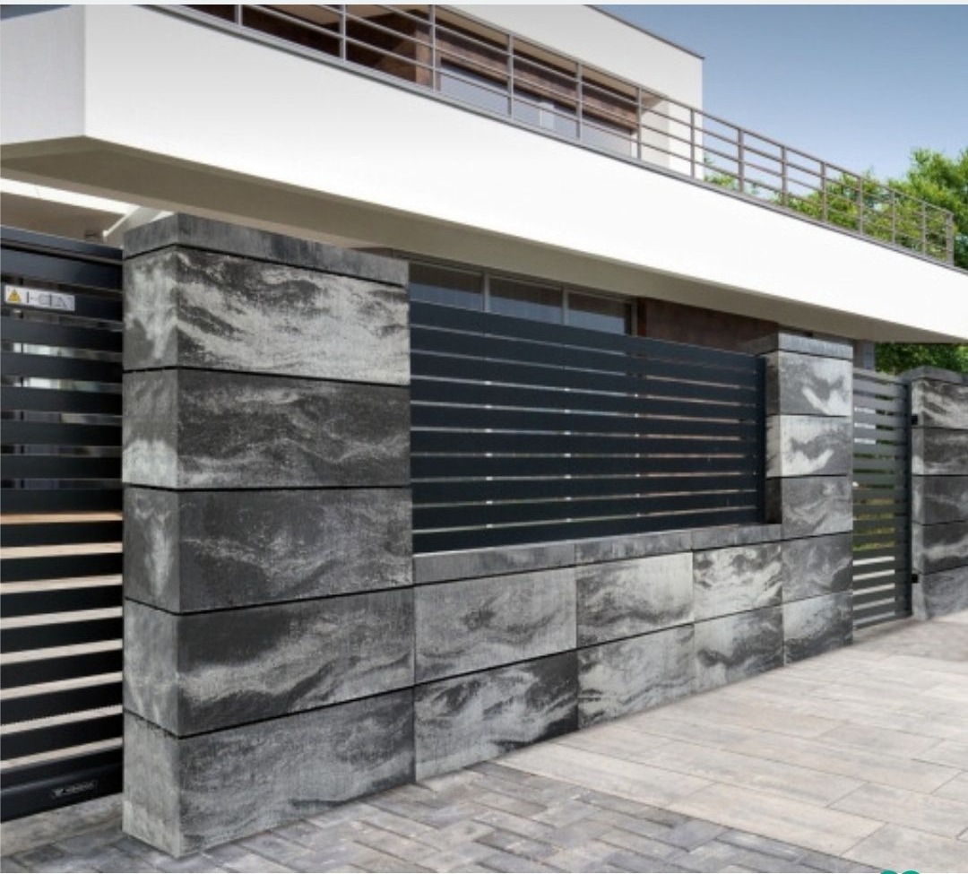 Nowoczesne ogrodzenie z betonowych bloków i metalowych paneli, zintegrowane z bramą wjazdową. Minimalistyczny design, szara kolorystyka, na tle domu.